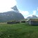 A plain with wood paneled buildings and a single large mountain peak in the distance